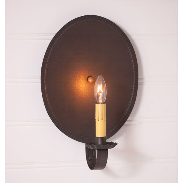 Oval primitive tin wired sconce with one lit candelabra bulb