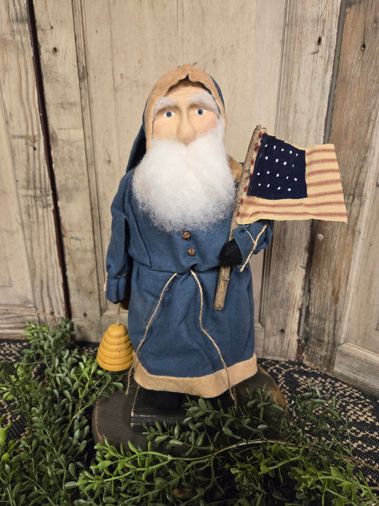 Primitive Small Santa with Blue Coat Holding Bee Skep with Flag