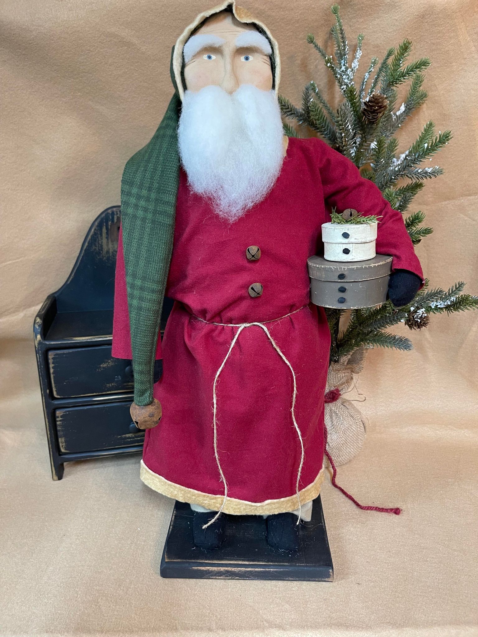 Primitive santa wearing red coat holding pantry boxes